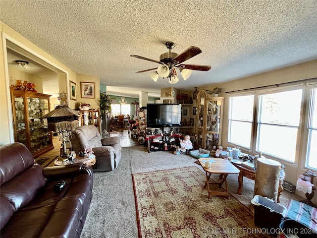 living room featuring ceiling fan, a textured ceiling, and carpet