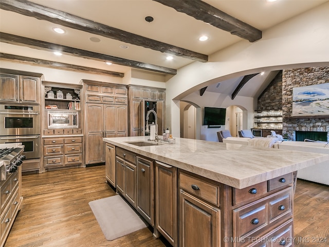 kitchen featuring arched walkways, dark wood-type flooring, appliances with stainless steel finishes, and open floor plan