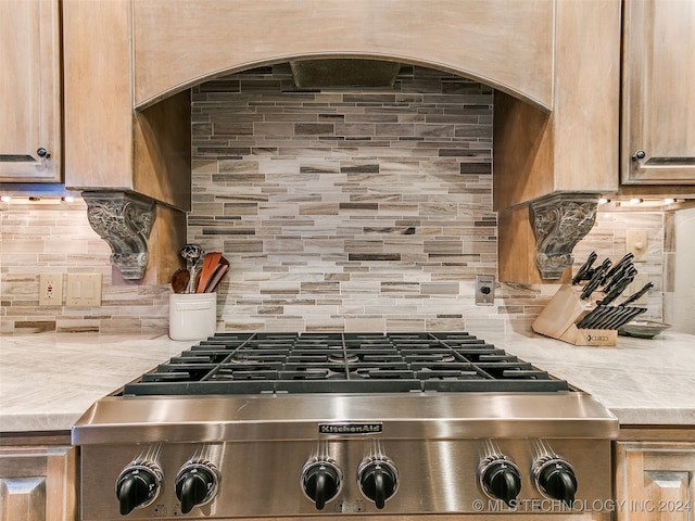 details featuring stainless steel gas stovetop and tasteful backsplash