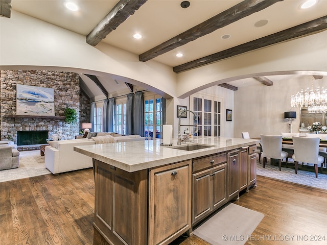 kitchen featuring dark wood-type flooring, light stone countertops, arched walkways, and a sink