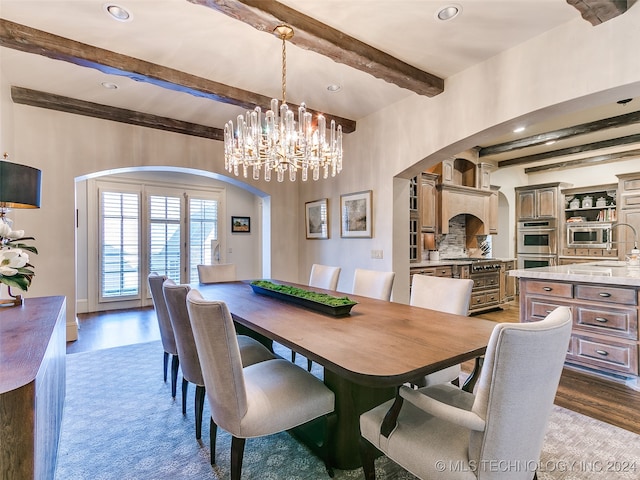 dining room featuring beamed ceiling, arched walkways, a notable chandelier, and wood finished floors