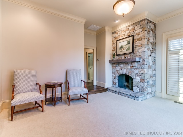 sitting room with a stone fireplace, carpet flooring, visible vents, and ornamental molding