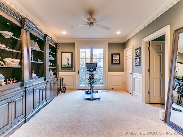 exercise room featuring a decorative wall, ornamental molding, carpet, and ceiling fan