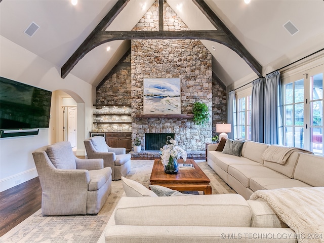 living area featuring visible vents, arched walkways, beamed ceiling, and wood finished floors