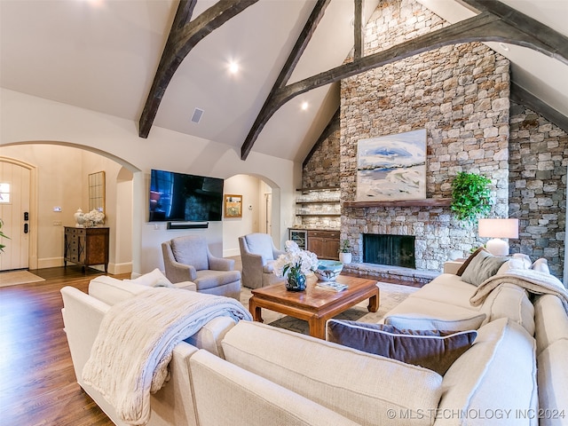 living area featuring arched walkways, beamed ceiling, high vaulted ceiling, and wood finished floors