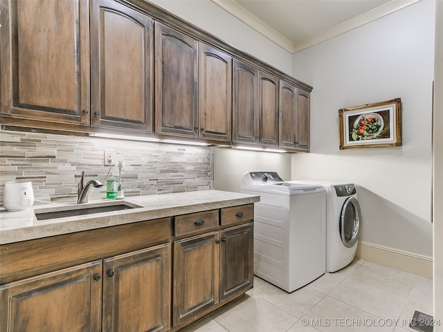 washroom with a sink, washing machine and dryer, cabinet space, crown molding, and light tile patterned floors