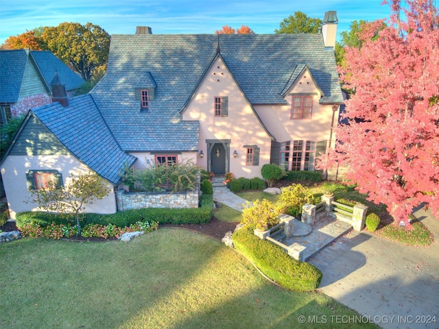 view of front of home featuring a front lawn, a chimney, and stucco siding