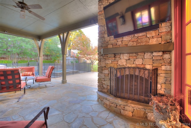 view of patio / terrace featuring an outdoor living space with a fireplace, a ceiling fan, and fence