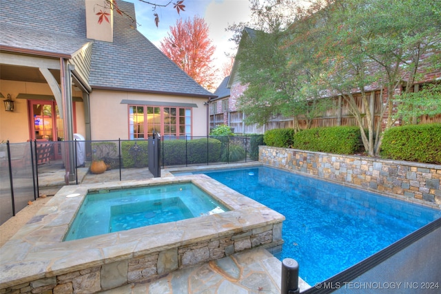 view of swimming pool featuring an in ground hot tub and fence