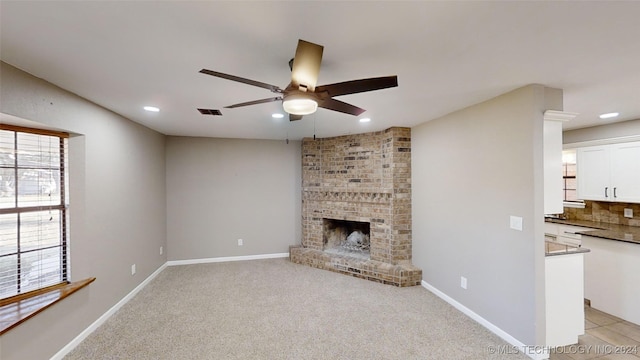 unfurnished living room featuring light carpet, a brick fireplace, and ceiling fan