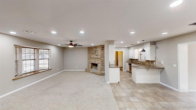 unfurnished living room featuring light colored carpet, a brick fireplace, ceiling fan, and sink