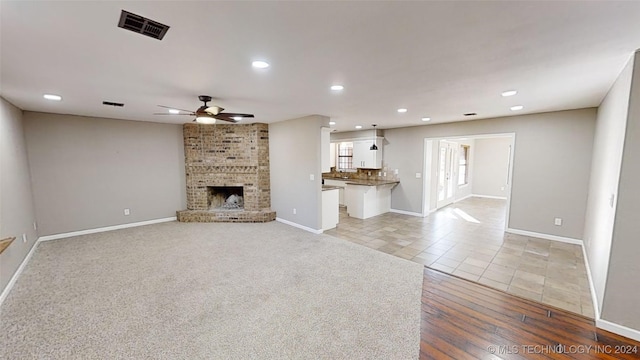 unfurnished living room with ceiling fan, light tile patterned floors, and a brick fireplace