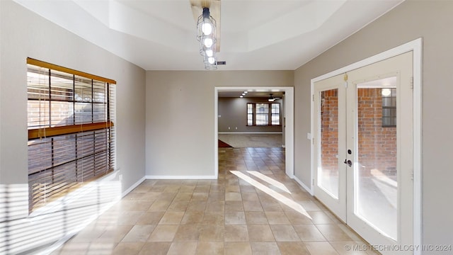 unfurnished dining area with french doors and a raised ceiling