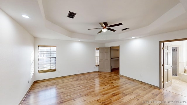 empty room featuring light hardwood / wood-style flooring, a raised ceiling, and ceiling fan