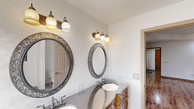 bathroom featuring toilet, vanity, and hardwood / wood-style flooring