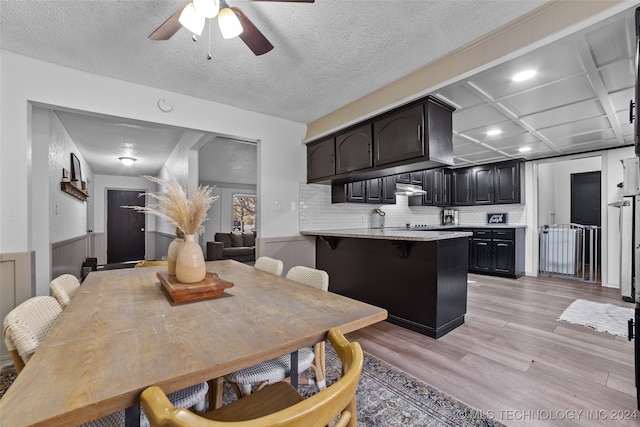 dining space featuring coffered ceiling, a textured ceiling, ceiling fan, and light hardwood / wood-style flooring