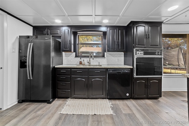 kitchen with light hardwood / wood-style floors, a healthy amount of sunlight, black appliances, and tasteful backsplash