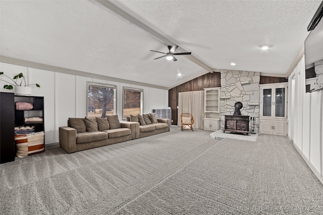 living room featuring wood walls, ceiling fan, carpet, a wood stove, and lofted ceiling with beams