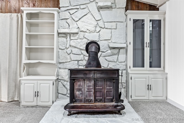 room details featuring carpet flooring, wood walls, and a wood stove