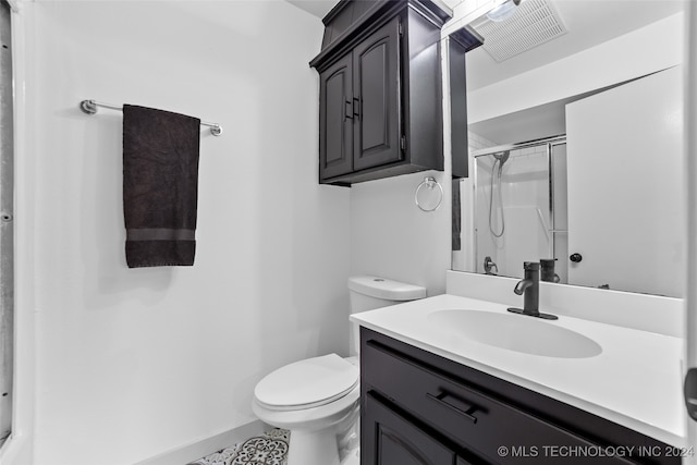 bathroom featuring tile patterned flooring, an enclosed shower, vanity, and toilet