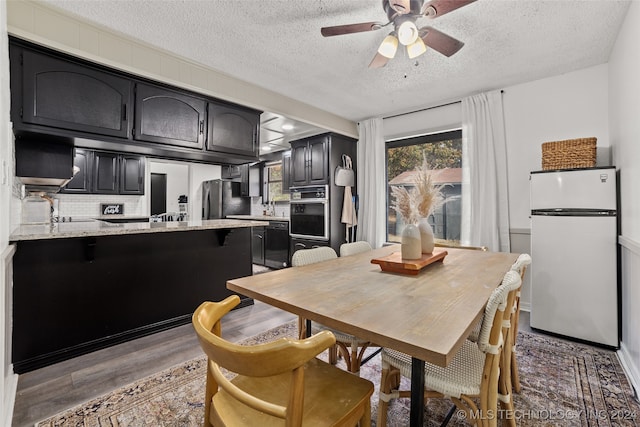 dining room featuring ceiling fan, a textured ceiling, and dark hardwood / wood-style flooring