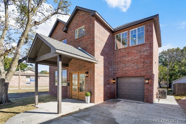 front of property featuring a garage, central AC, and french doors