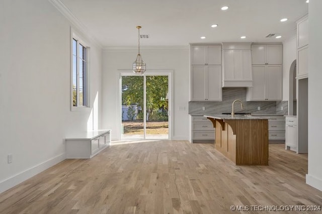 kitchen with an island with sink, white cabinets, and light hardwood / wood-style flooring