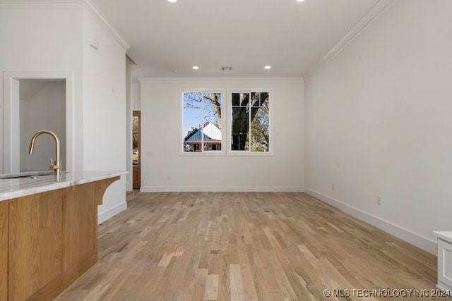 unfurnished living room featuring sink, light hardwood / wood-style flooring, and ornamental molding