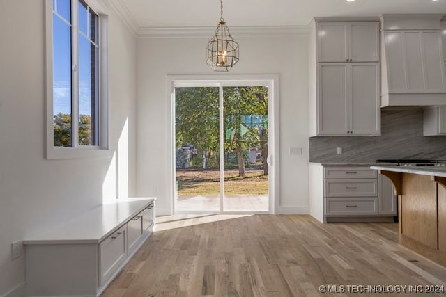 unfurnished dining area with light wood-type flooring, a notable chandelier, and ornamental molding