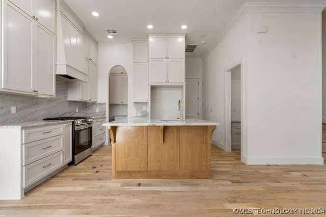 kitchen with a center island with sink, light wood-type flooring, white cabinetry, and stainless steel range oven