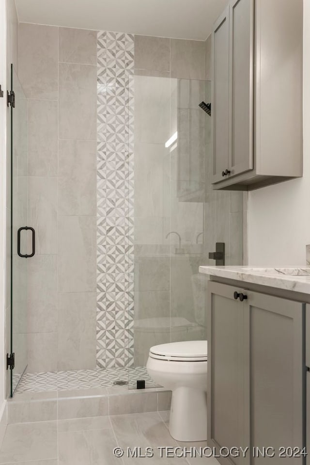 bathroom featuring toilet, an enclosed shower, vanity, and tile patterned floors