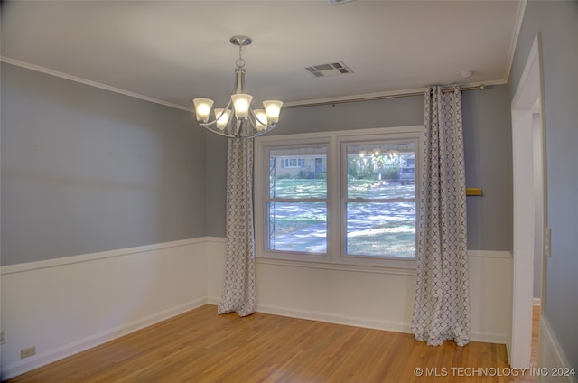 empty room featuring ornamental molding, wood-type flooring, and a notable chandelier