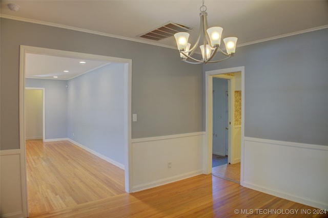 spare room with hardwood / wood-style floors, a notable chandelier, and crown molding