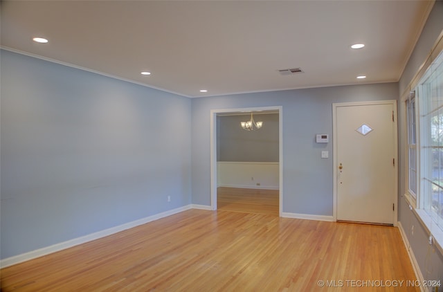 entrance foyer featuring light hardwood / wood-style floors, crown molding, and an inviting chandelier