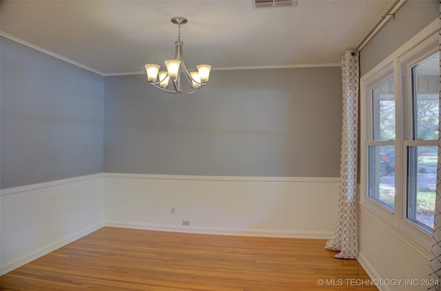 unfurnished room featuring a healthy amount of sunlight, light hardwood / wood-style flooring, crown molding, and a notable chandelier