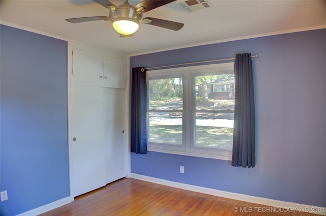 empty room featuring ceiling fan, wood-type flooring, and crown molding