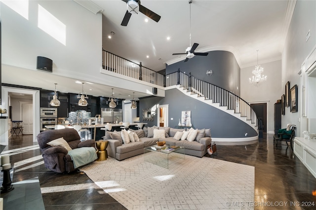 living room with a towering ceiling, ceiling fan with notable chandelier, and crown molding