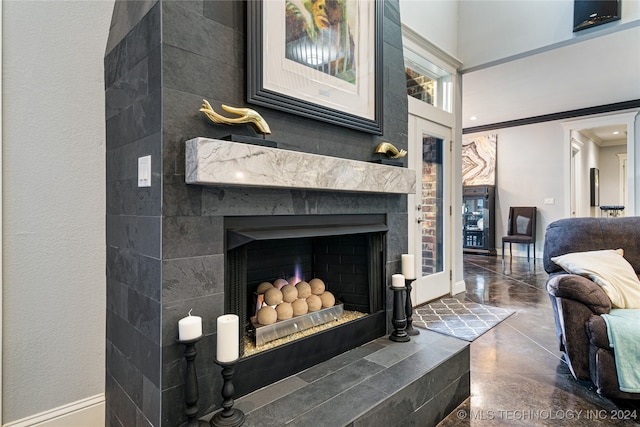 interior details with ornamental molding, a tile fireplace, and concrete floors