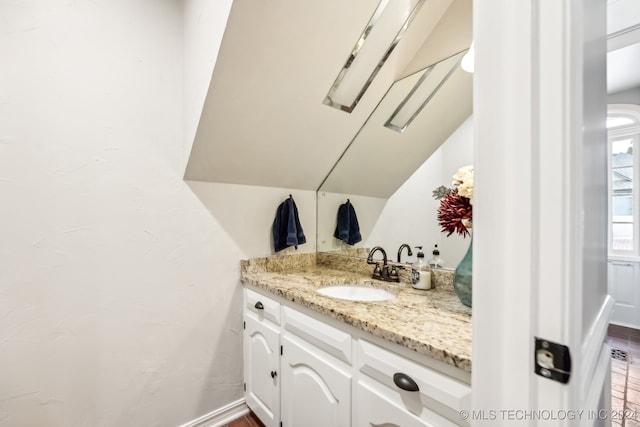 bathroom with vanity, hardwood / wood-style flooring, and vaulted ceiling