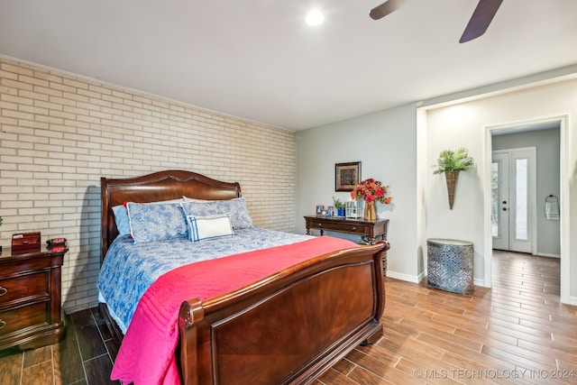 bedroom with hardwood / wood-style floors, brick wall, and ceiling fan