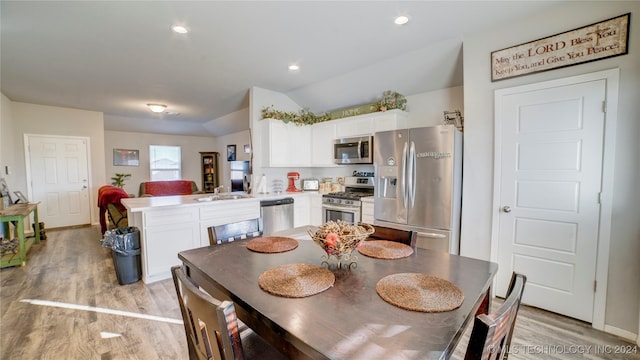 dining space featuring light hardwood / wood-style floors, vaulted ceiling, and sink