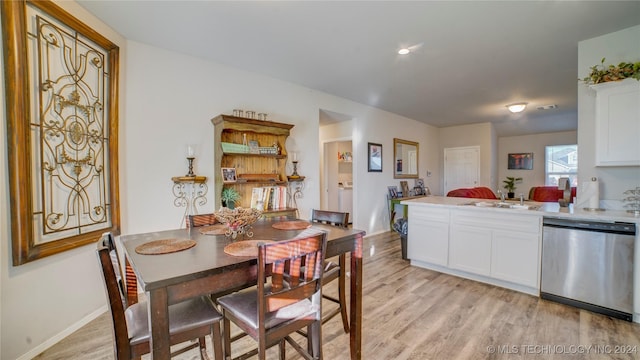 kitchen featuring light wood-type flooring, white cabinetry, stainless steel dishwasher, and sink