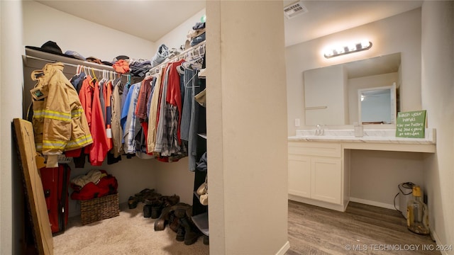 walk in closet with sink and light hardwood / wood-style flooring