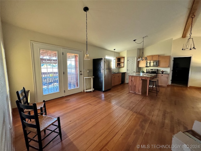 kitchen featuring hardwood / wood-style floors, hanging light fixtures, vaulted ceiling with beams, a kitchen island, and stainless steel appliances