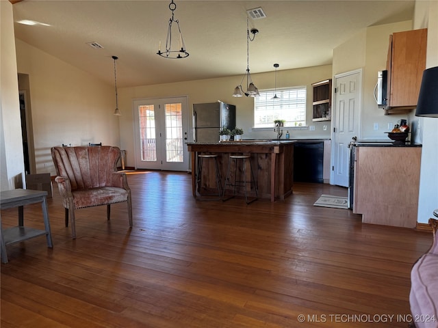 kitchen with dark wood-type flooring, stainless steel appliances, a kitchen breakfast bar, pendant lighting, and vaulted ceiling