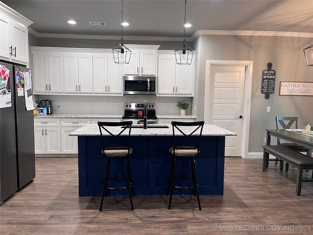 kitchen with an island with sink, hanging light fixtures, white cabinetry, and appliances with stainless steel finishes