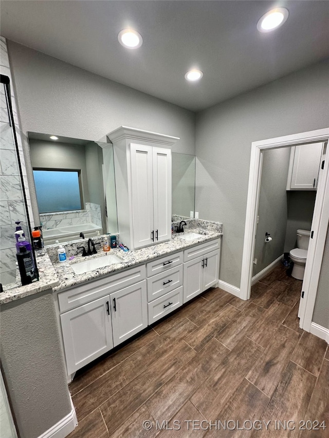 bathroom featuring toilet, vanity, a bathtub, and hardwood / wood-style flooring