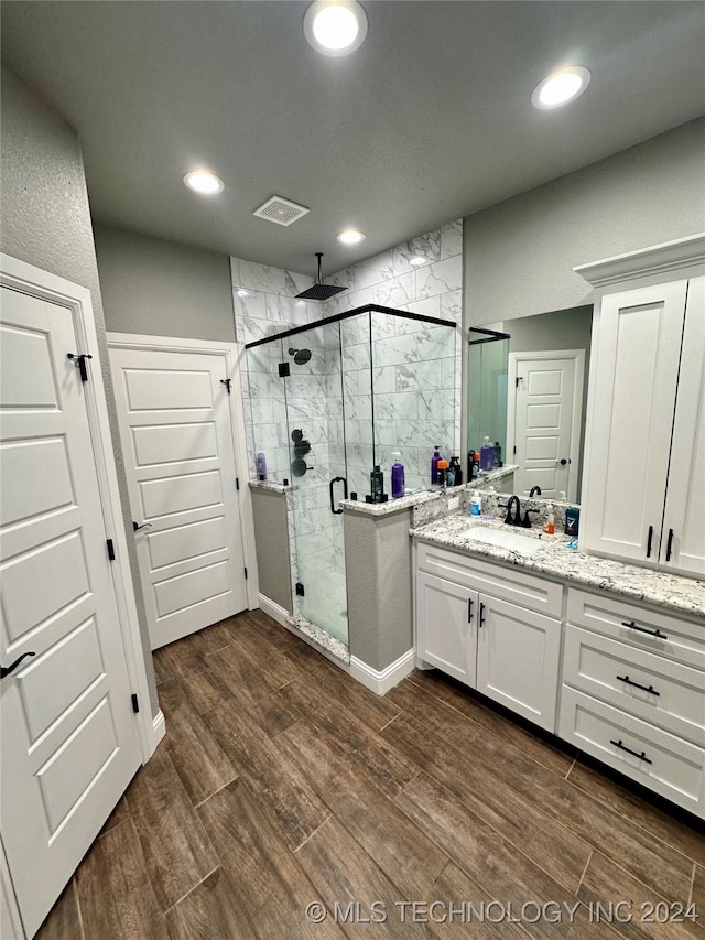 bathroom with walk in shower, wood-type flooring, and vanity