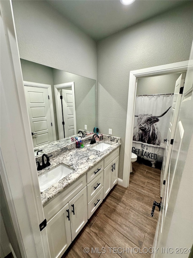 bathroom featuring wood-type flooring, toilet, vanity, and a shower with shower curtain