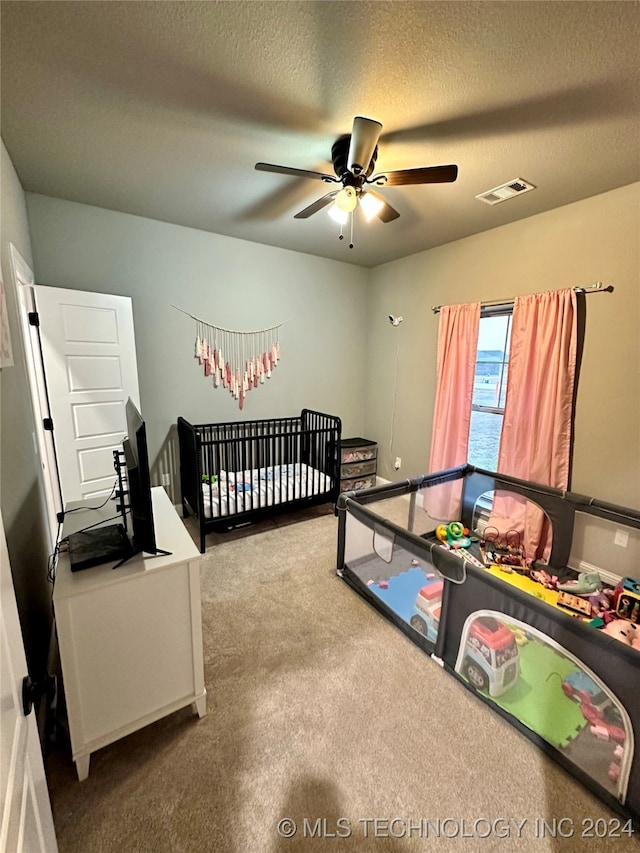 carpeted bedroom featuring ceiling fan and a textured ceiling